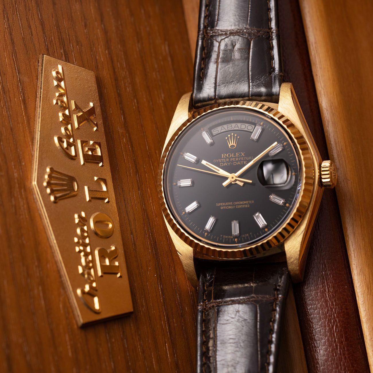 Lot 100 – Rolex Day-Date in yellow-gold reference 18 038, with black lacquered dial set with baguette hour markers.