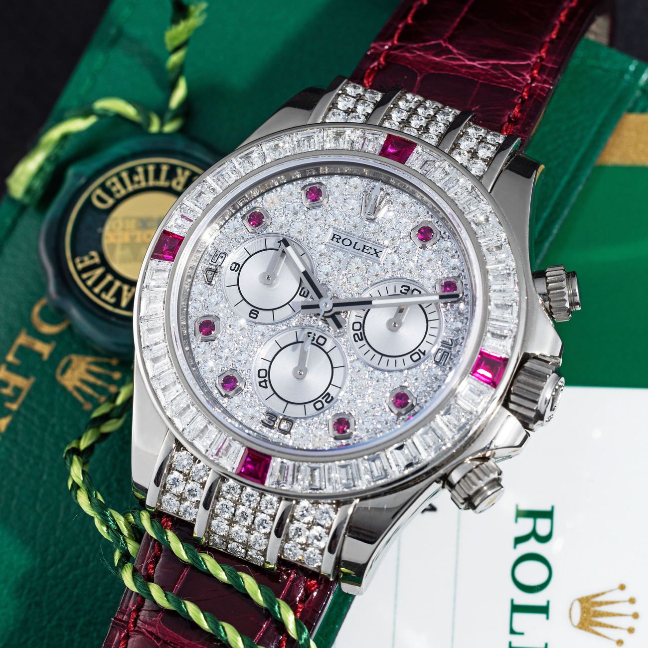 Lot 253 — ROLEX, Lavish, Extraordinary and Absolutely Rare, Daytona, Automatic Wristwatch in White Gold, Pavè Diamond and Rubies Set Dial, Baguette Diamond and Ruby Bezel, With Box and Papers, Reference 1165994RU – Estimate: € 150,000 – 300,000 – VIEW LOT